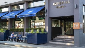 Exterior do Hotel Imperial com fachada moderna, área de estar ao ar livre e entrada visível.