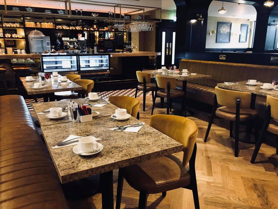 Een restaurant met meerdere tafels en zitjes, voorzien van koffieautomaten en diverse kopjes en schotels.