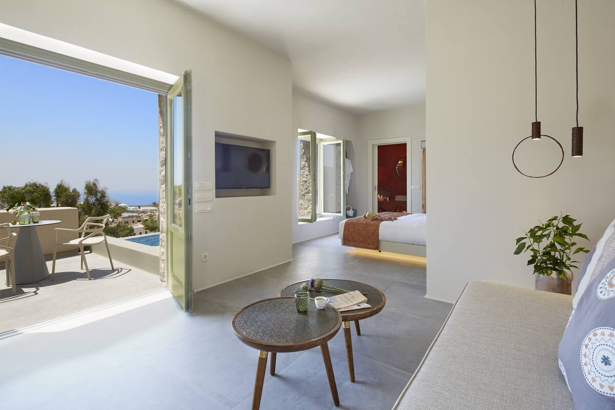 A modern living room with a sofa, two small tables, and a view of the ocean.