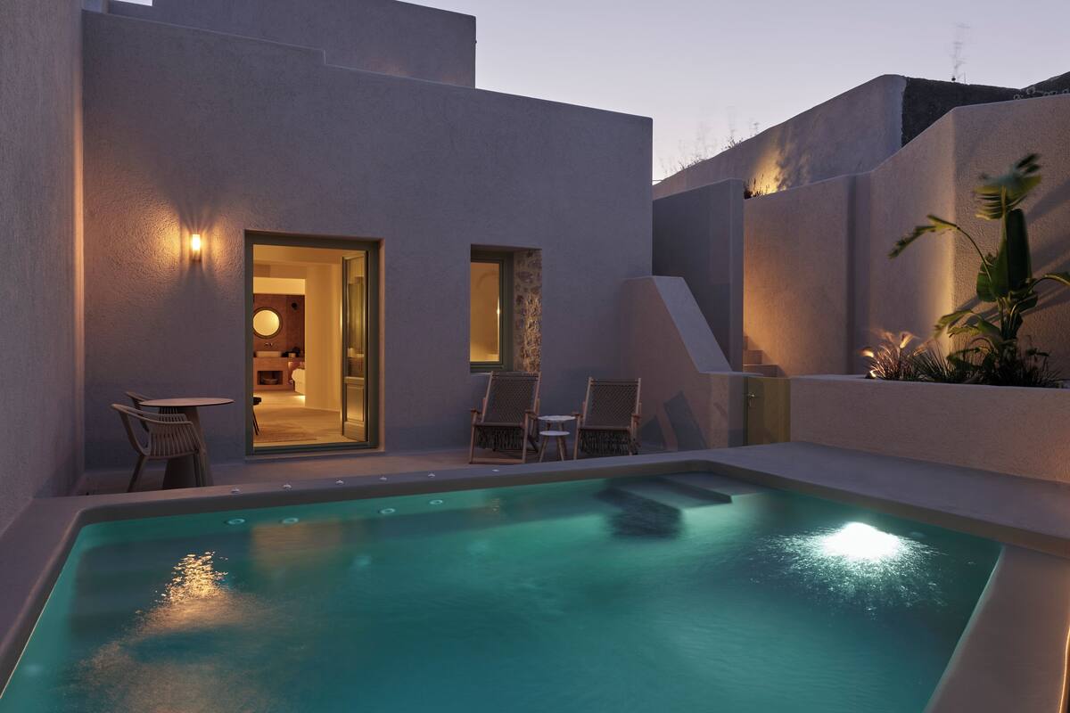 A modern outdoor pool area with a clear view of the pool, two lounge chairs, and a small table.