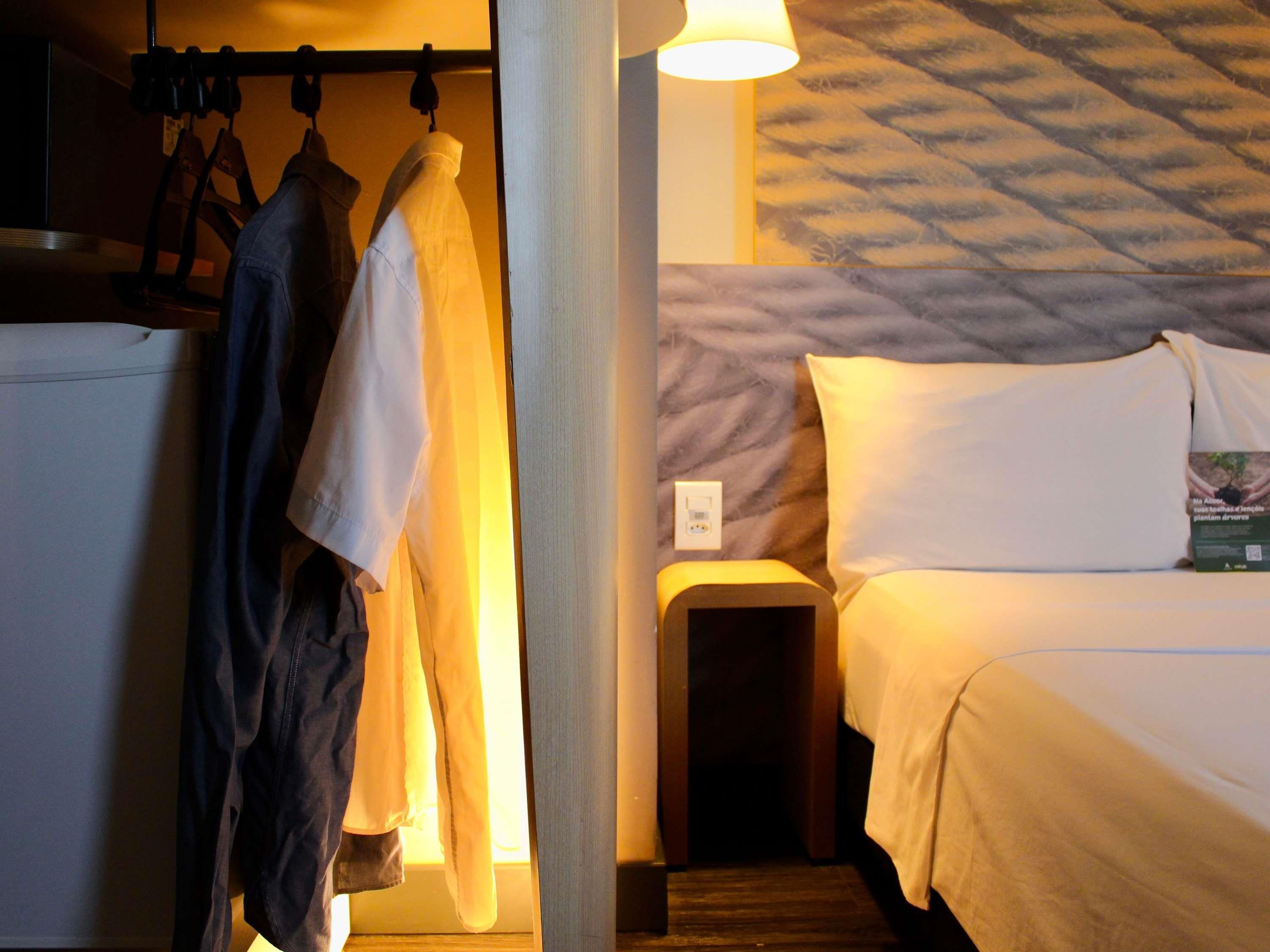 Et hotelværelse med en seng, et natbord og en lampe på væggen.