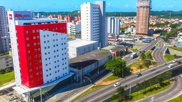 A hotel with a red and white facade, multiple floors, and a parking area.