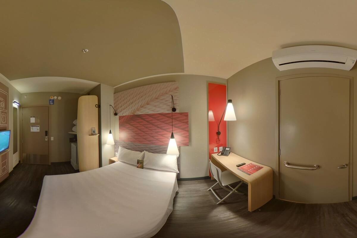 Une chambre d’hôtel équipée d’un lit, d’un bureau, d’une chaise et d’un appareil de climatisation.