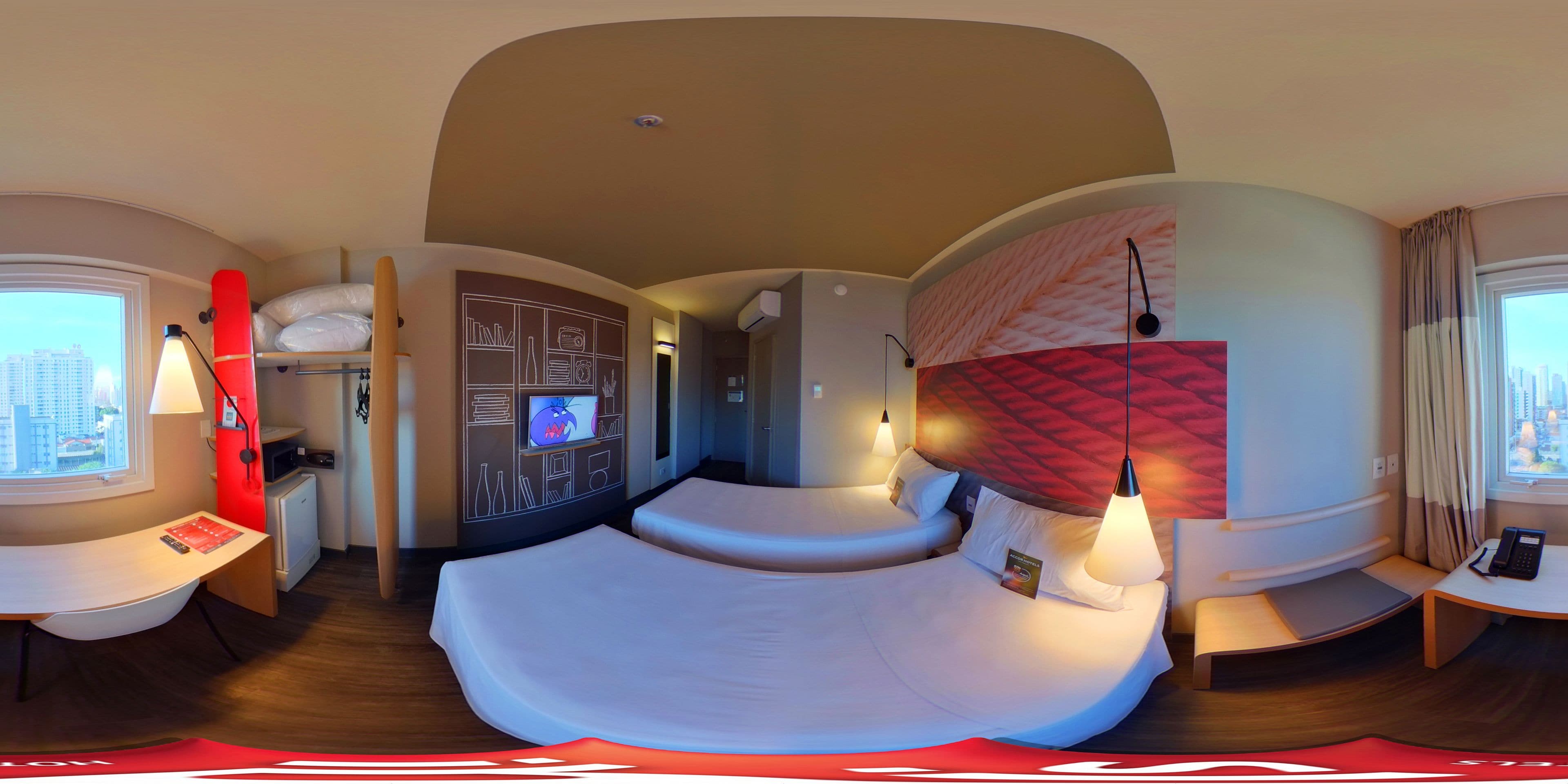 Una habitación de hotel moderna con techo curvo, cama con pared de acento roja, escritorio con lámpara y vista a la ciudad.