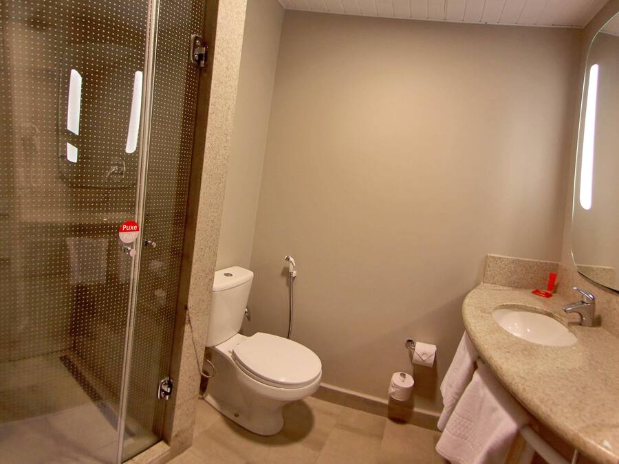 A bathroom with a toilet, shower, and sink.