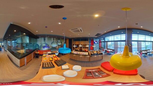 A modern restaurant with a central buffet, seating areas, and large windows.