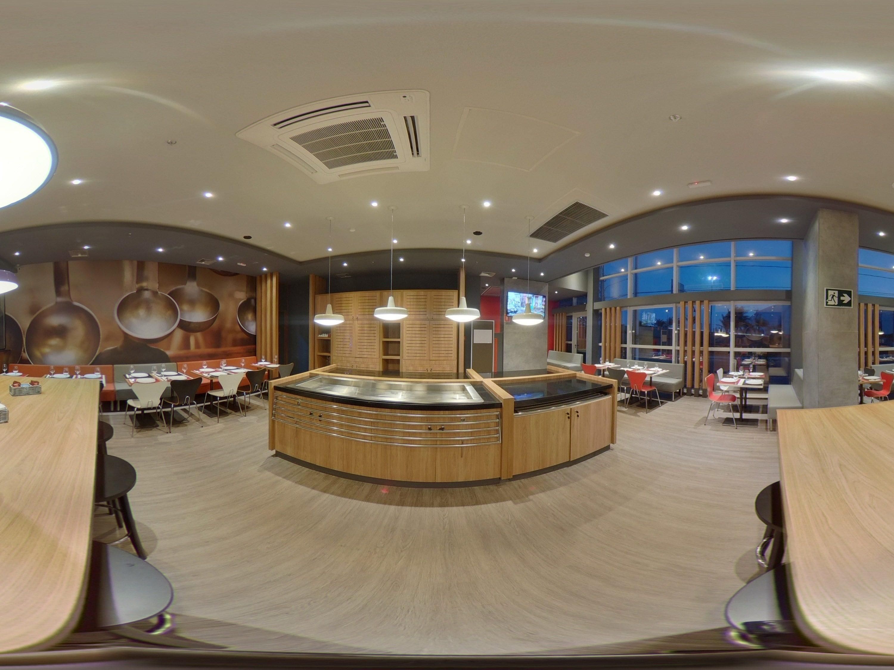 Un interior de restaurante moderno con una isla central, varias mesas y un ventanal que ofrece vistas.