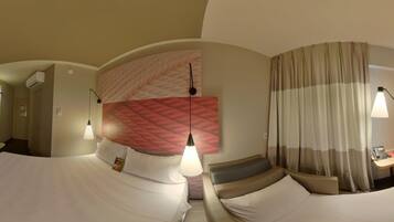A hotel room with a curved bed, a large wall mural, and a separate seating area with a lamp.