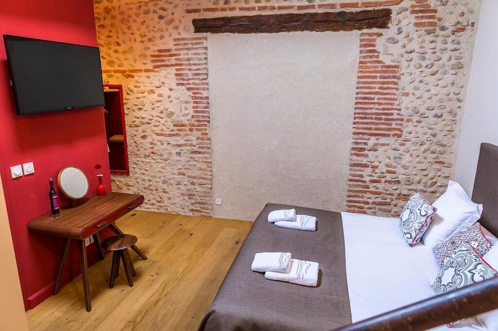 Une chambre avec un lit, un bureau et un téléviseur fixé au mur.