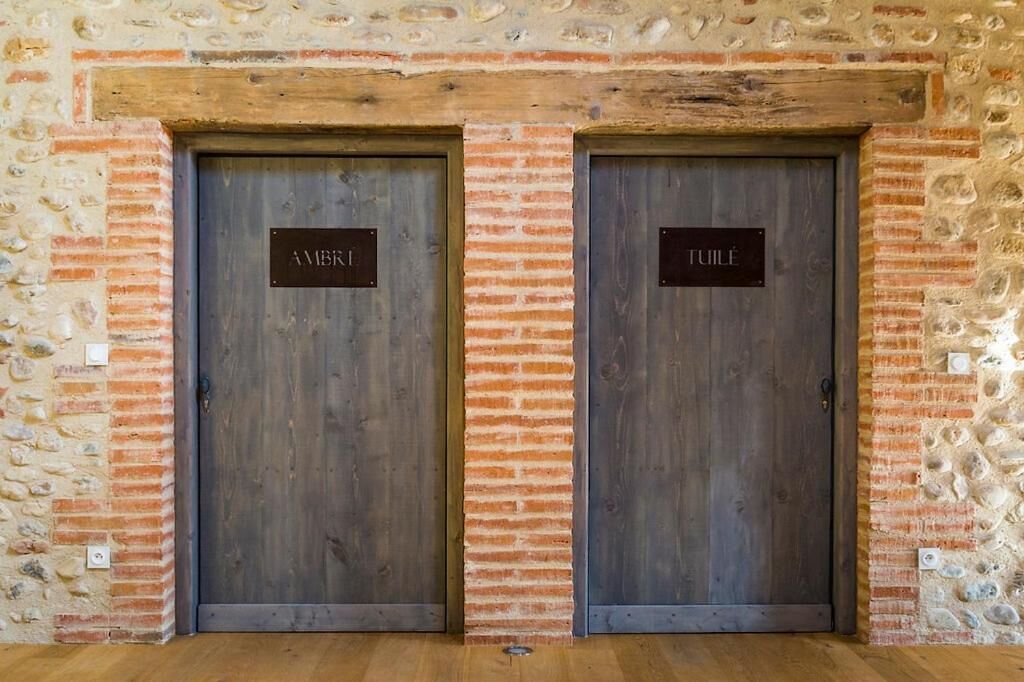 Two wooden doors with metal plaques, set in a stone and brick wall.