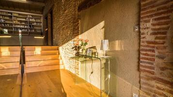 Une pièce avec un plancher en bois, une table en verre ornée d’un cadre photo et d’un vase, et un mur en briques.