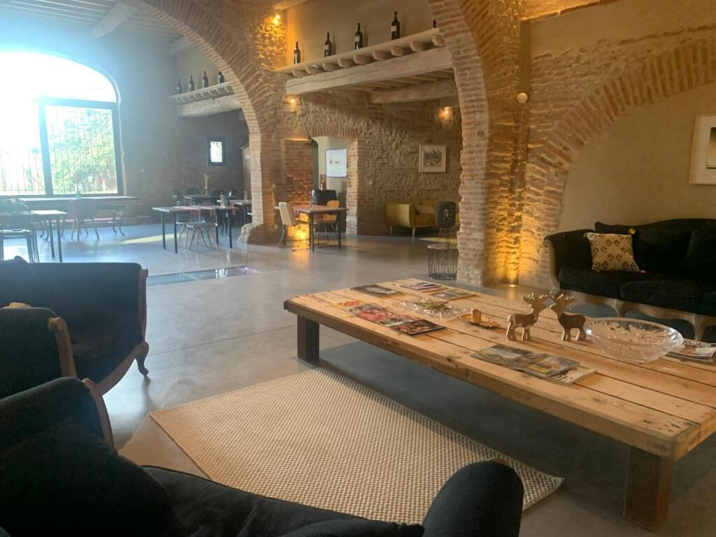 A spacious interior with a high ceiling, exposed brick walls, and a large window providing natural light.