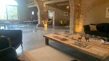 A spacious interior with a high ceiling, exposed brick walls, and a large window providing natural light.