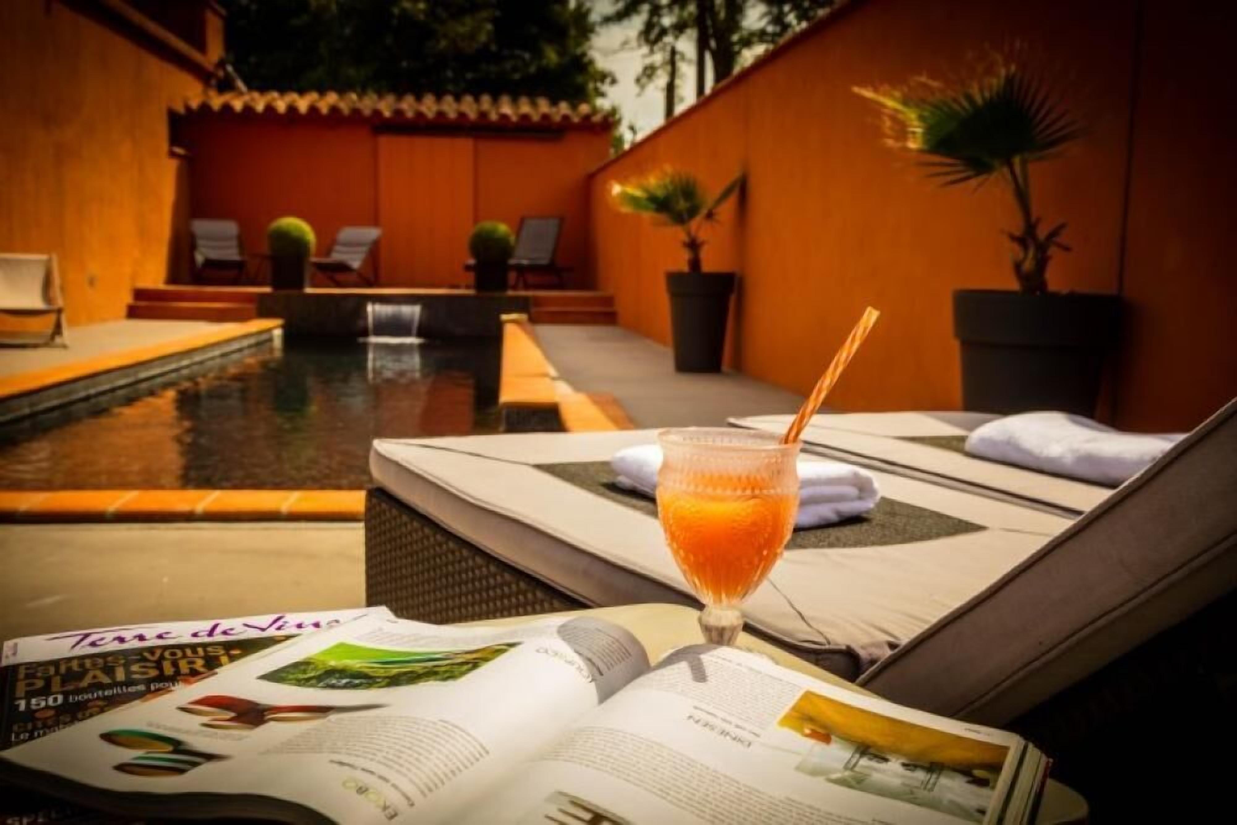 Et loungeområde ved poolen med appelsinjuice, et magasin og liggestole.