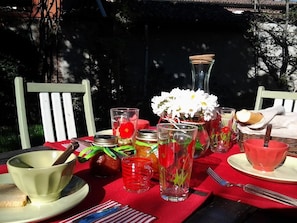 A dining table set outdoors with various glassware, a vase with flowers, and a basket with bread. - Il Pettirosso (Certosa di Pavia)