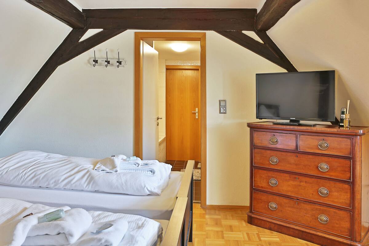 A bedroom with a bed, wooden dresser, and a television.