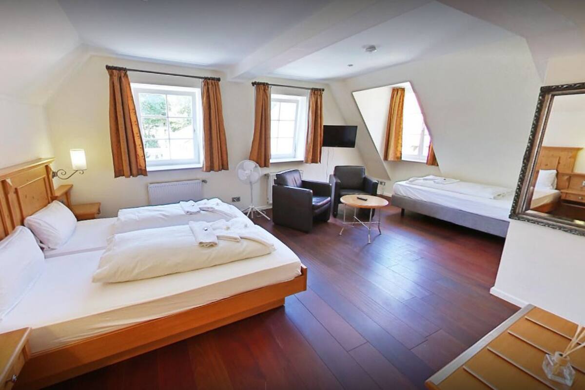 A hotel room with two beds, a desk, a chair, a TV, and a large mirror.