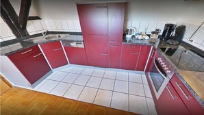 Een compacte keuken met rode kastjes, een roestvrijstalen spoelbak en een inbouwoven.