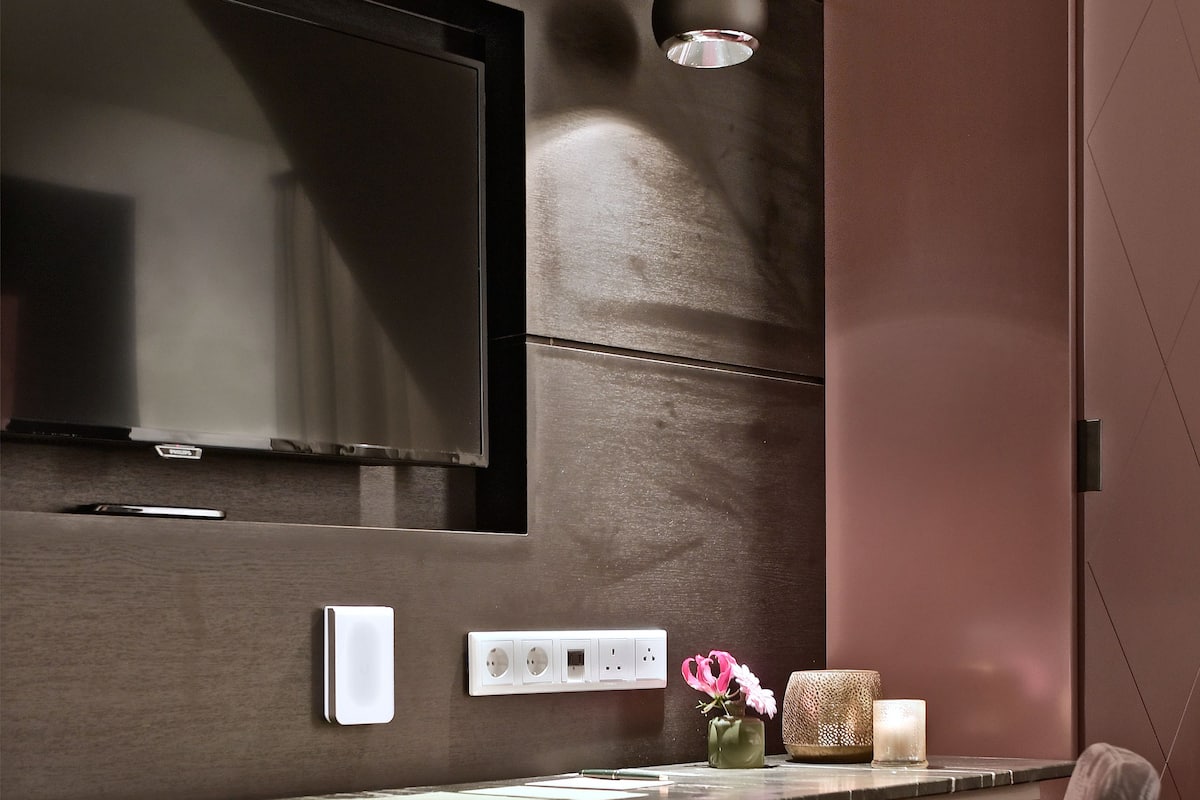 Una habitación moderna con televisor de pantalla plana en la pared, encimera de mármol, una silla y una mesita con objetos decorativos.