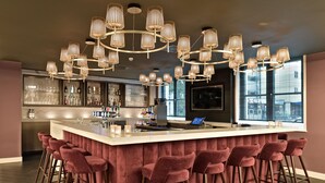 Eine moderne Bar mit einer zentralen Theke, mehreren Barhocker und einer ungewöhnlichen Leuchte.