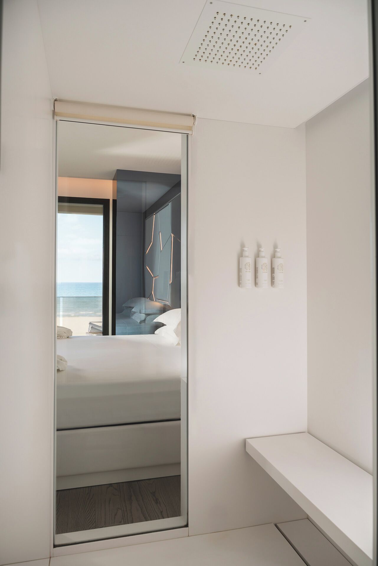 Une chambre d’hôtel moderne dotée d’un grand lit, d’une vue sur la plage, d’un dressing et d’un petit coin salon.