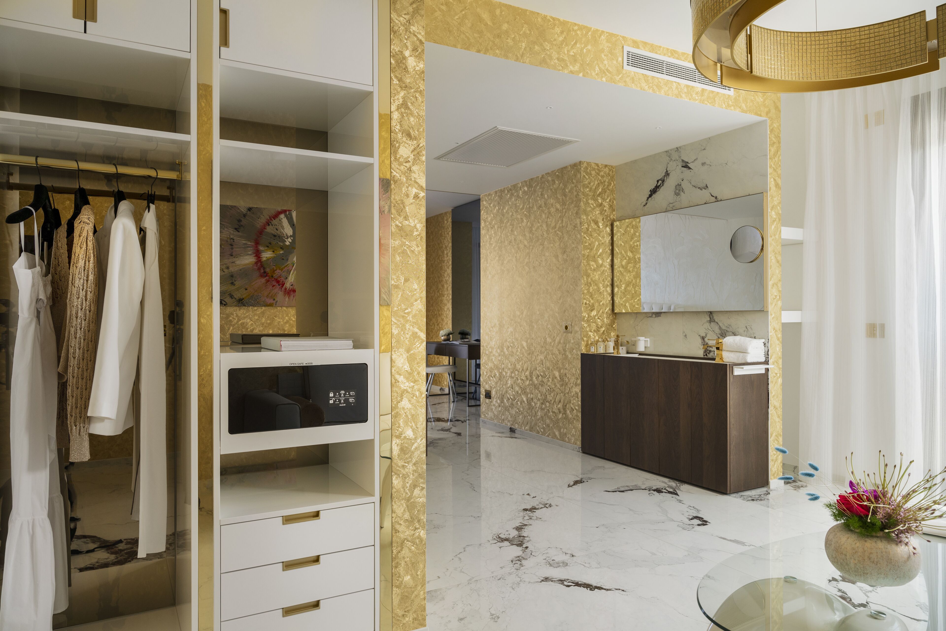 A modern bathroom with a marble floor, a vanity with a mirror, and a glass table with a vase.