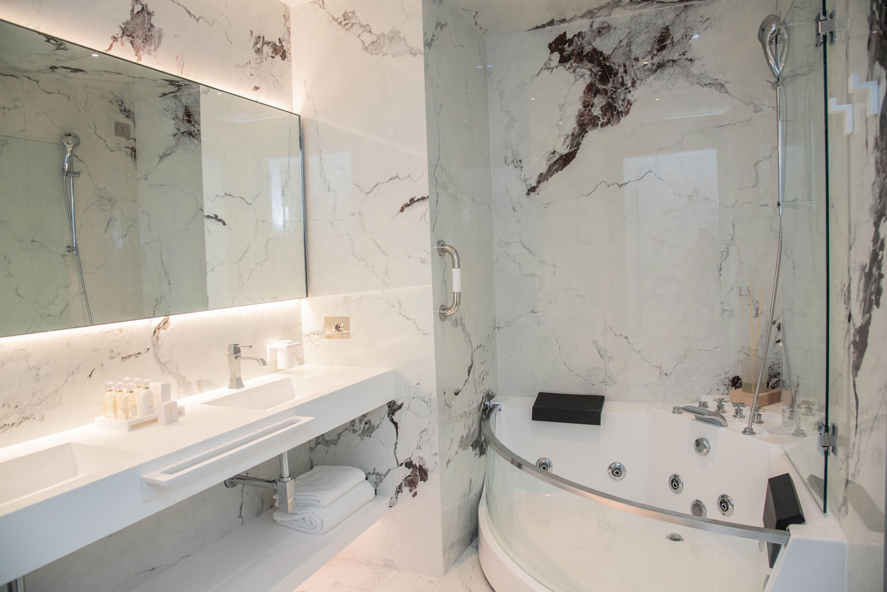 A modern bathroom with a marble sink, a large bathtub, and a glass-enclosed shower area.