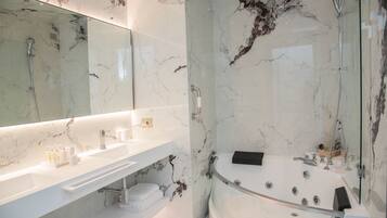A modern bathroom with a marble sink, a large bathtub, and a glass-enclosed shower area.