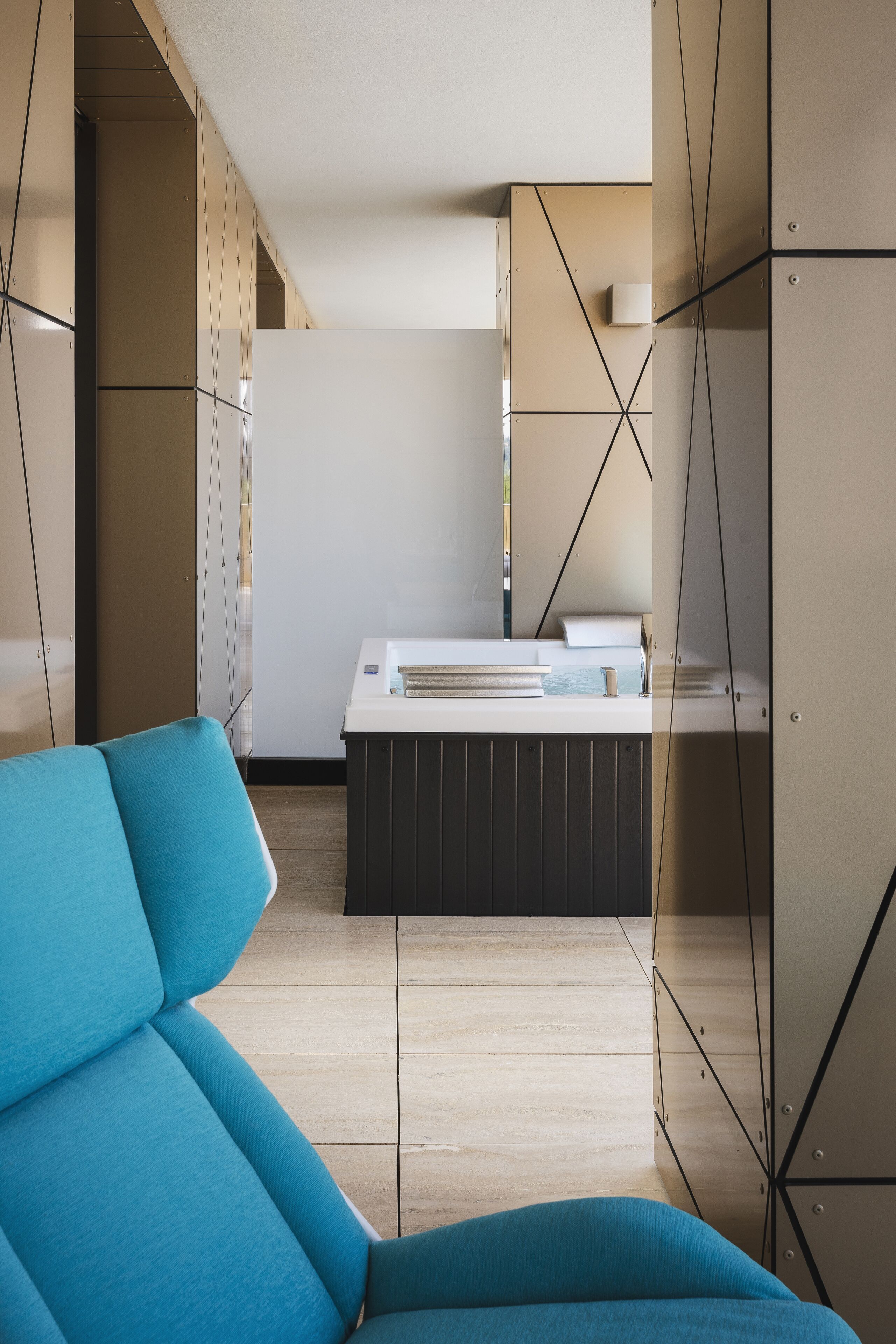 A modern room with a blue sofa, a kitchen area with a white countertop, and a wooden cabinet.