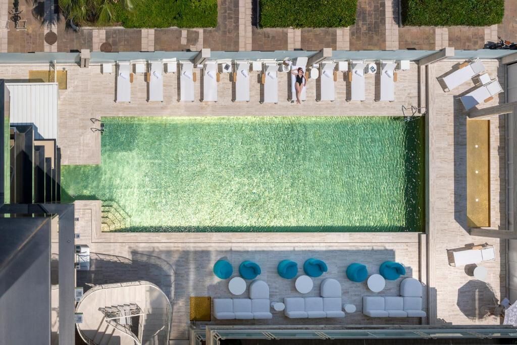 An aerial view of a rooftop pool area with lounge chairs and a seating area.