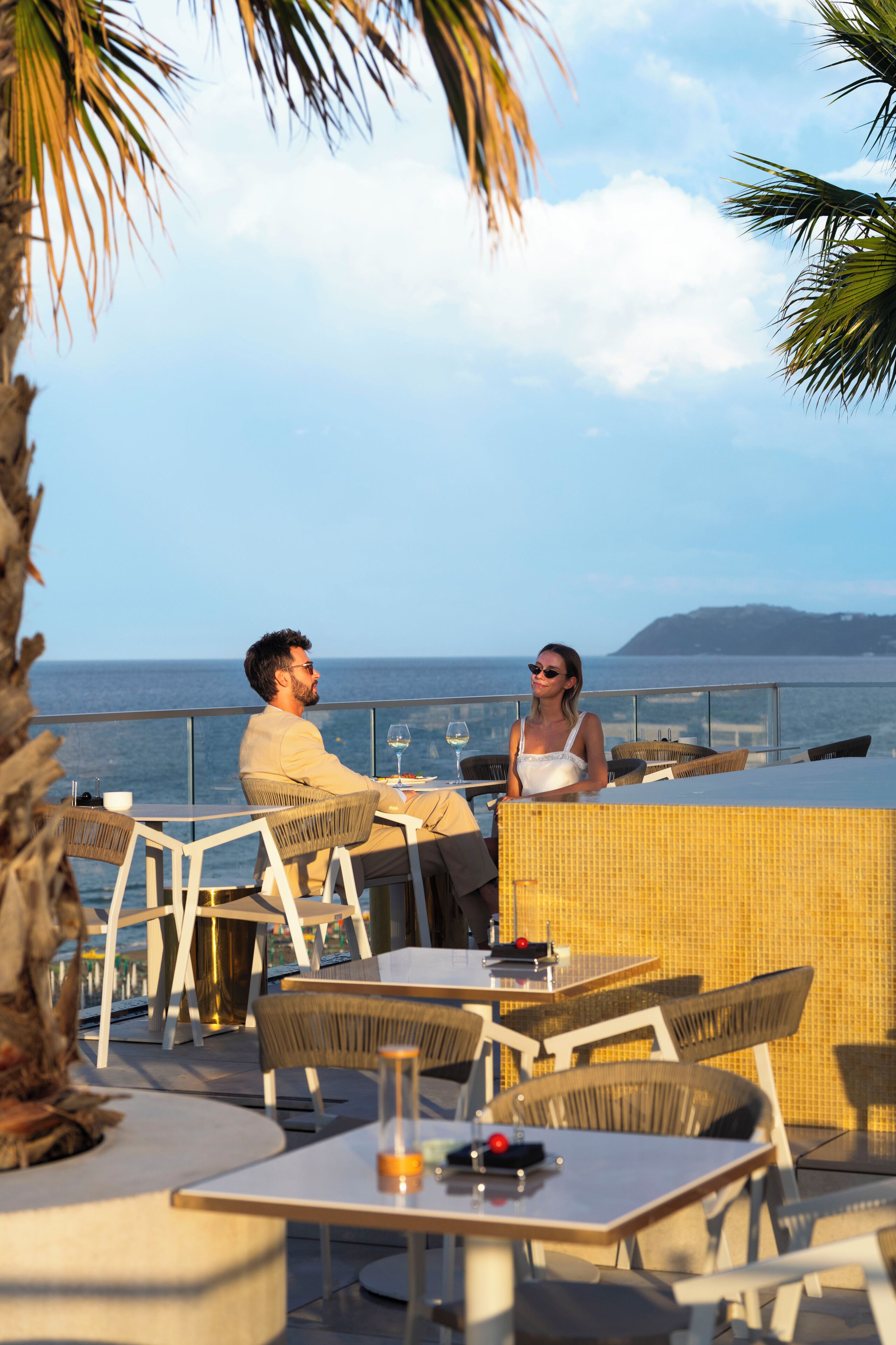Ein Paar speist an einem Tisch im Freien mit Blick auf das Meer.