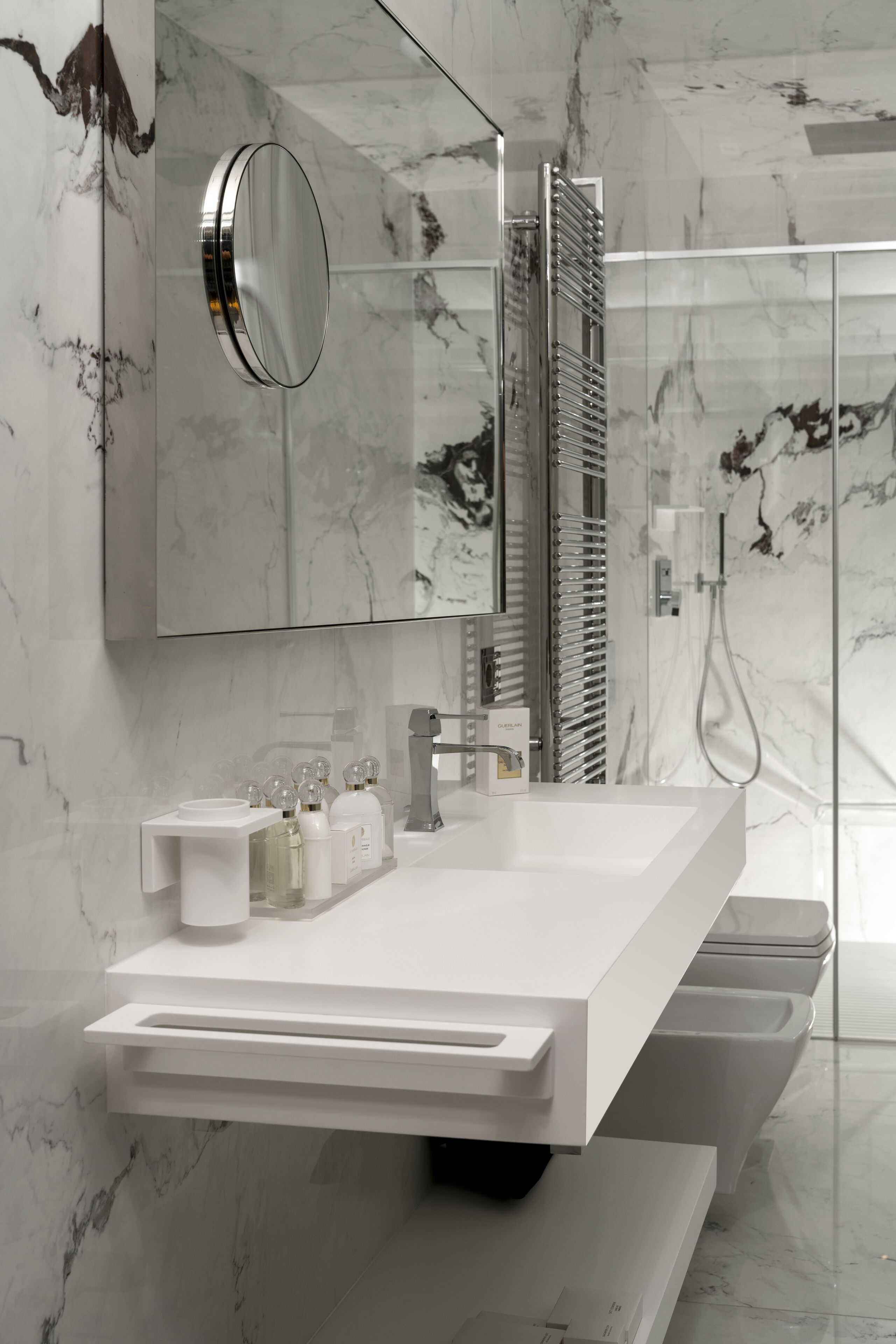 Un bagno moderno con un mobile lavabo bianco, uno specchio grande e un box doccia in vetro.