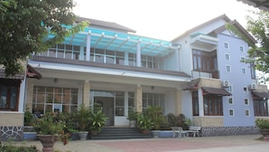 A two-story building with a covered entrance, potted plants, and a bench outside. - Quang Nam University Guesthouse (Da Nang)