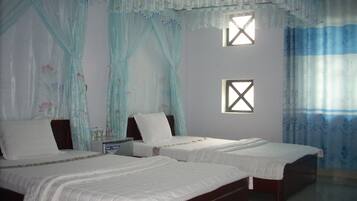 A room with two beds, a small window, and a curtain with floral patterns.