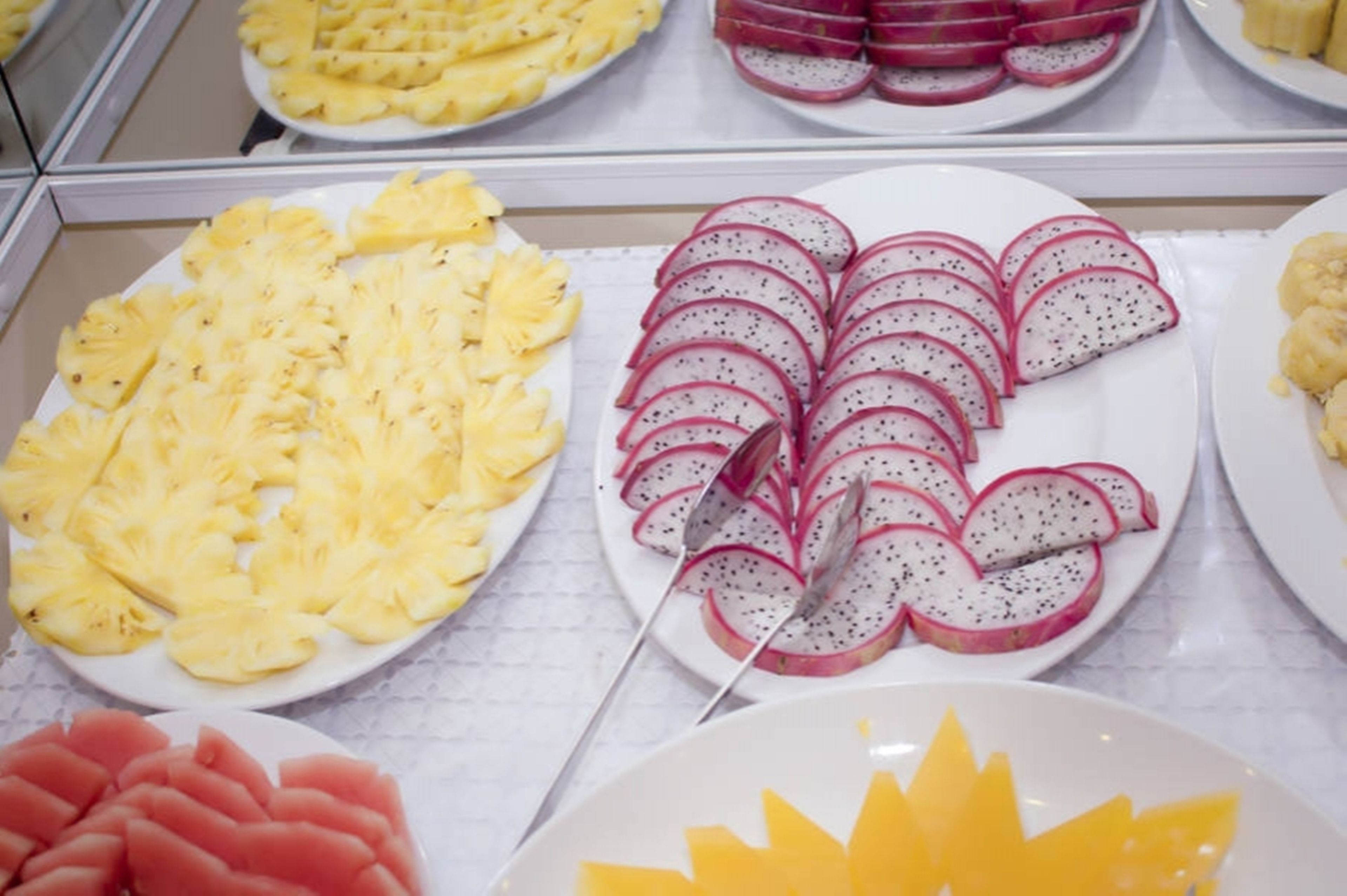 Esposizione di frutta a fette, tra cui ananas, pitaya e anguria.