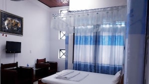 A hotel room with a bed, a desk, a chair, a television, and a window with curtains. - Quang Nam University Guesthouse (Da Nang)
