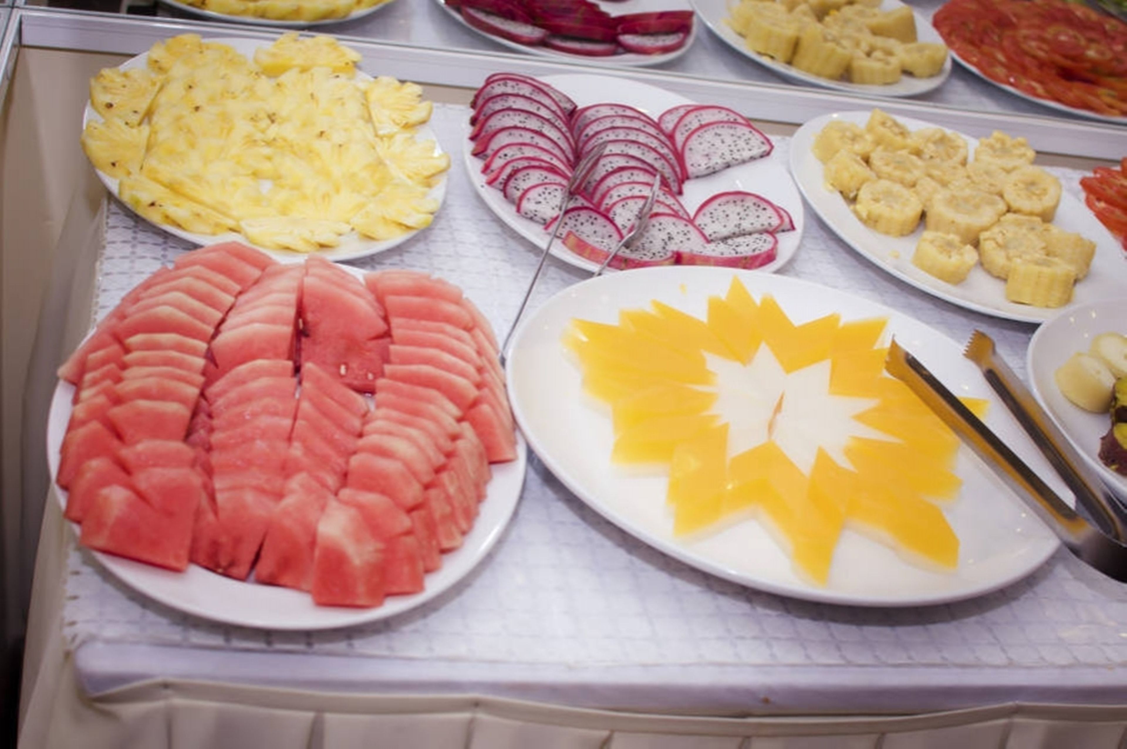 A display of sliced fruits including watermelon, pineapple, dragon fruit, and mango.