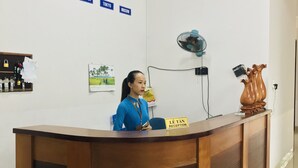 A reception desk with a clock, a sign indicating 'Lê Tân Reception', and a wall with city names. - Quang Nam University Guesthouse (Da Nang)