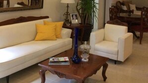 A living room with a chandelier, a sofa, a coffee table, and a dining area. - Casa Roces Bed and Breakfast (Legazpi)