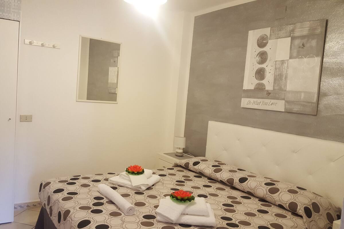 Un dormitorio con cama, espejo y una obra de arte en la pared.