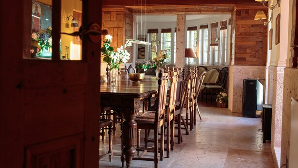 A dining area with a long wooden table, chairs, and a fireplace.