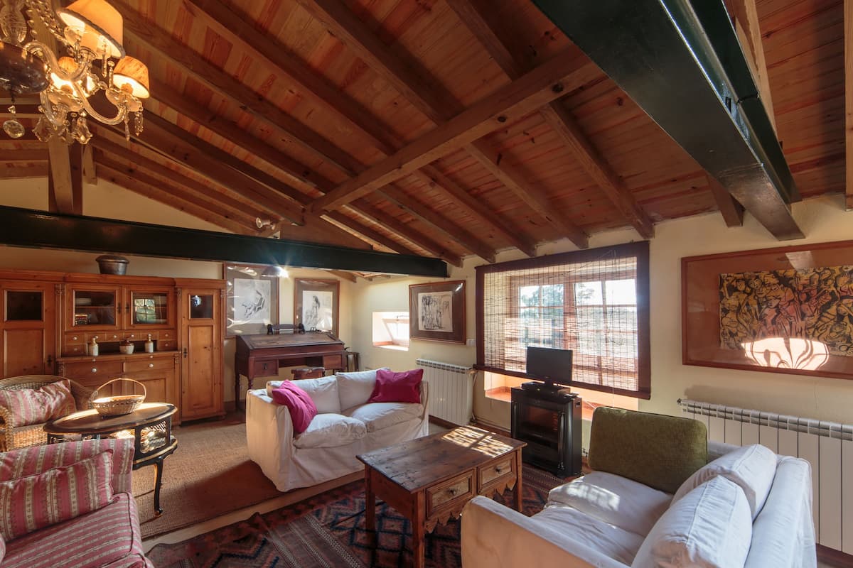 A cozy living room with wooden beams, a fireplace, and comfortable seating.