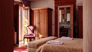 A room with two beds, a wooden wardrobe, a chair, and a mirror.