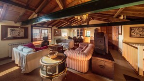 A cozy, rustic room with wooden beams, a sofa, a small table, and a staircase leading to another level.