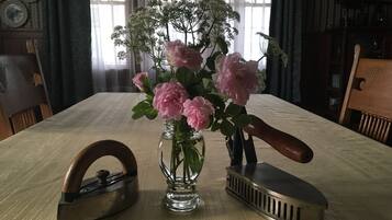 Una mesa de madera con un jarrón de flores rosas, un planchador de hierro antiguo y un planchador moderno.