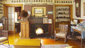 A traditional living room with a fireplace, wooden furniture, and a collection of clocks on the walls. - Old Iron Inn Bed and Breakfast (Caribou)