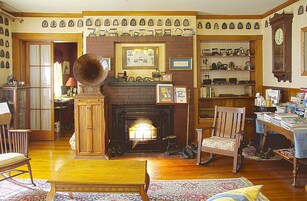 Un salón tradicional con chimenea, muebles de madera y una colección de relojes en las paredes.
