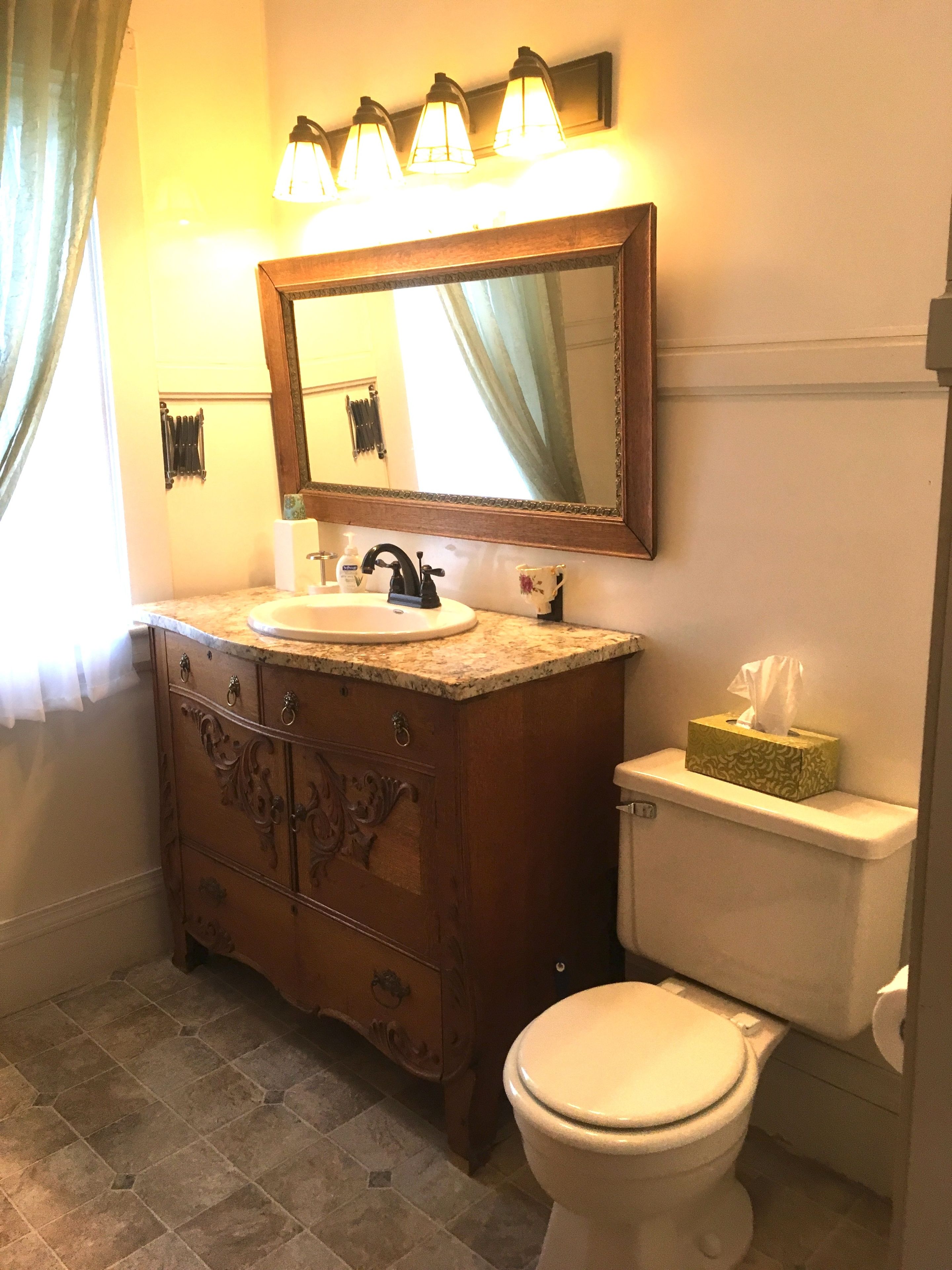 A bathroom with a wooden vanity, a sink, a mirror, and a toilet.