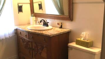 A bathroom with a wooden vanity, a sink, a mirror, and a toilet.