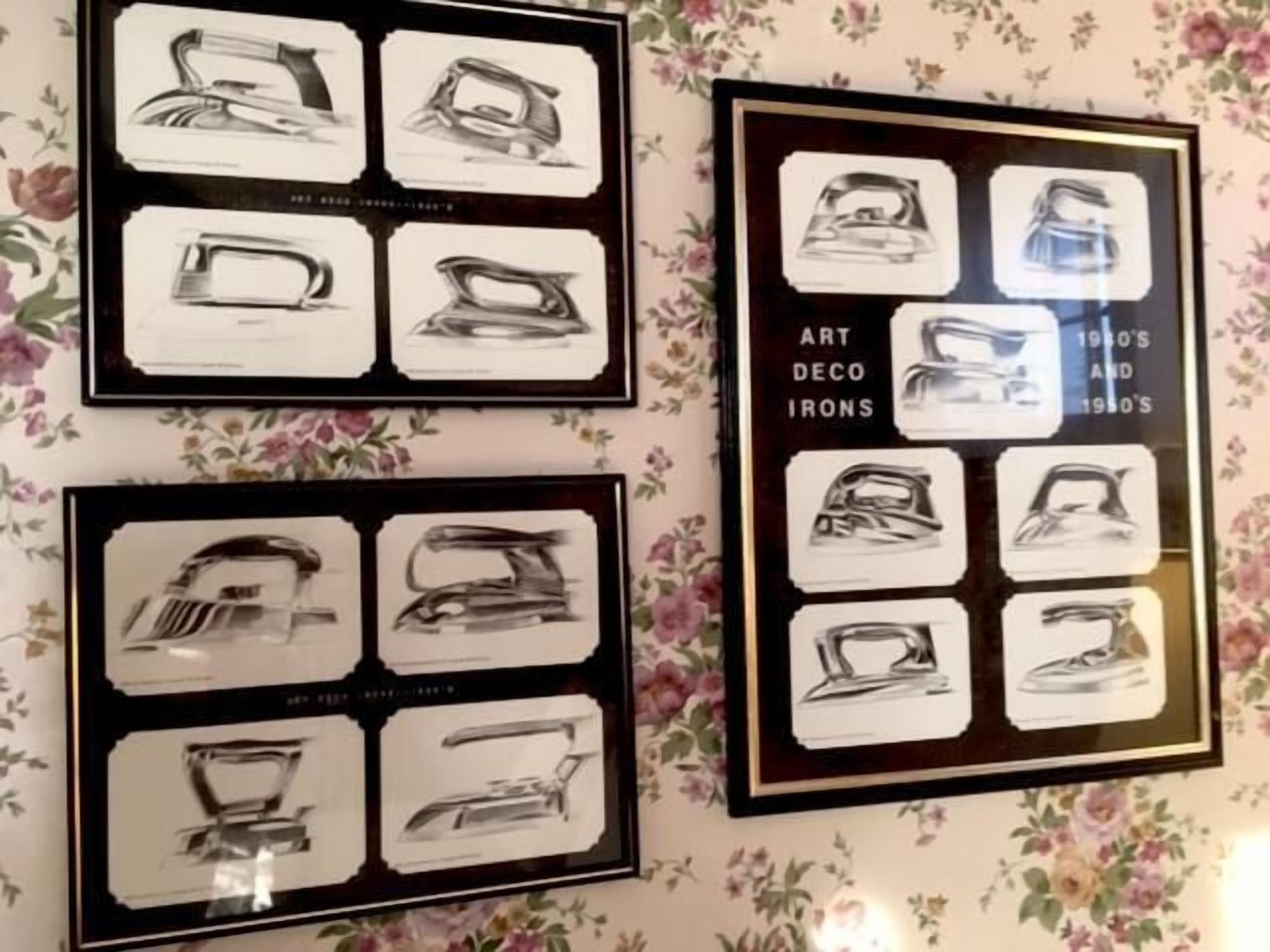 Un mur orné de tableaux représentant des fers à repasser, dont certains sont accompagnés d’une légende indiquant la décennie à laquelle ils appartiennent, comme les années 1950 et 1960.